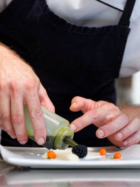 Male chef garnishing his dish, ready to serve clipart