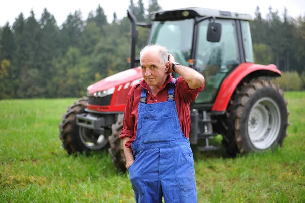 Jordbrukaren framför hans traktor — Stockfoto