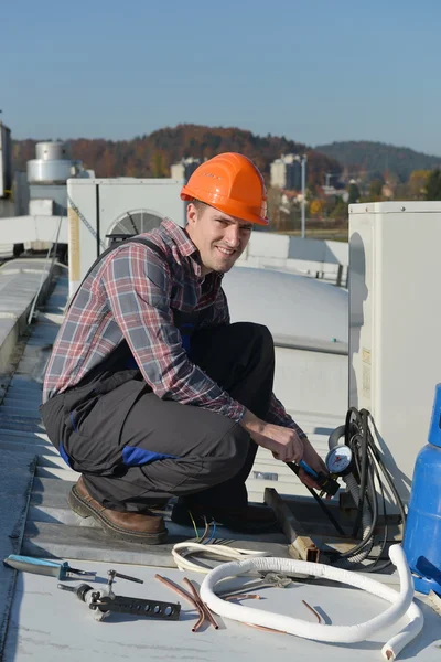 Giovane riparatore sul tetto sistema di fissaggio aria condizionata — Foto Stock