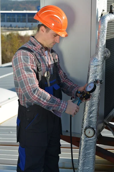 Jonge reparateur op het dak vaststelling van airconditioningsysteem — Stockfoto