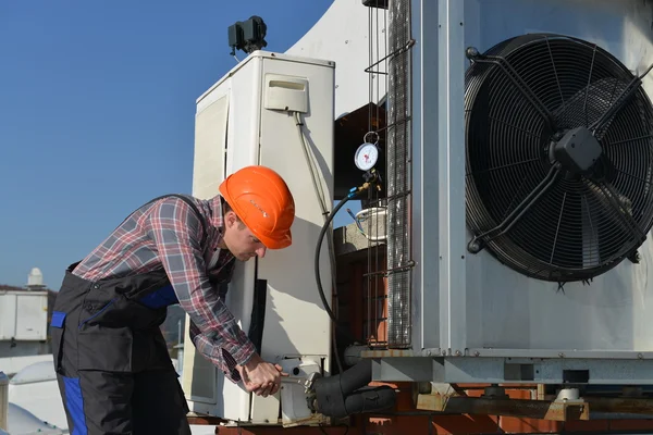 Młody mechanik na dachu ustalające system klimatyzacji Obraz Stockowy