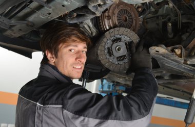 Auto mechanic working under the car clipart