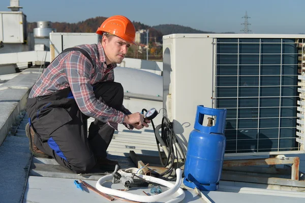 Jonge reparateur op het dak vaststelling van airconditioningsysteem — Stockfoto