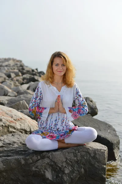 Young woman doing yoga on a rocky ocean shore — Stock Photo, Image