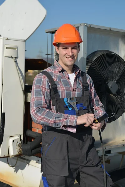 Unga reparatör på taket fästande luftkonditioneringssystem — Stockfoto