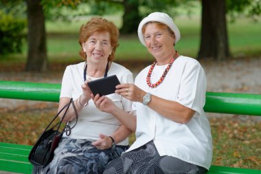 Two senior ladies reading news clipart