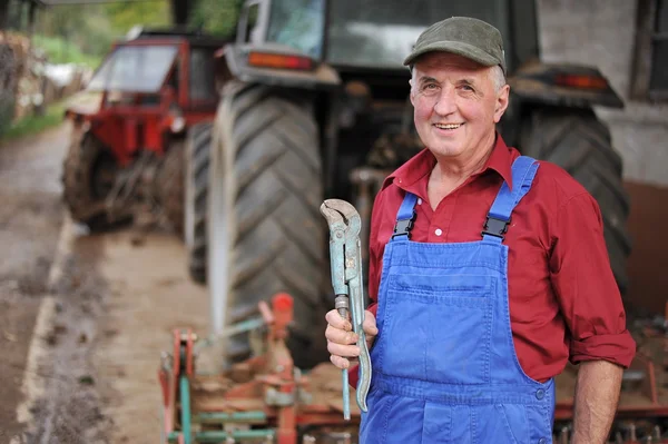 Fermierul îşi repară tractorul roşu Imagine de stoc