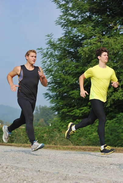 Två unga idrottare jogging / kör i parken Stockbild