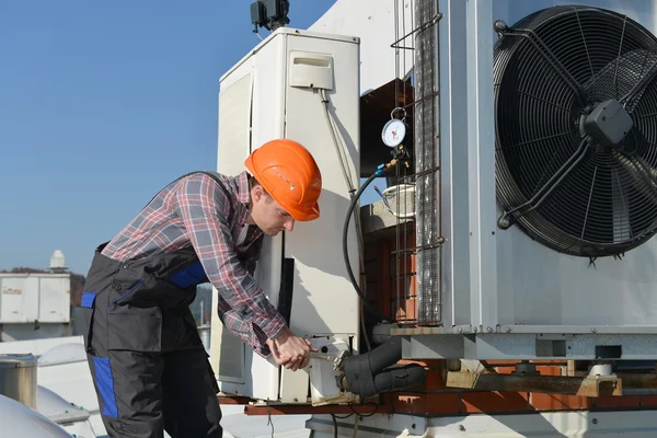 Young repairman fixing air conditioning system