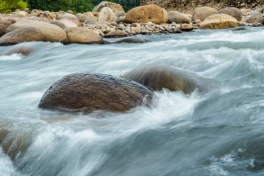 Kayalar arasında hızlı ve güçlü su akıyor.
