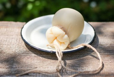 İtalyan scamorza peyniri kırsal tarzda beyaz tabakla bahçedeki eski ahşap masada.