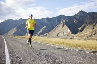 Dağ yolu üzerinde koşan genç adam