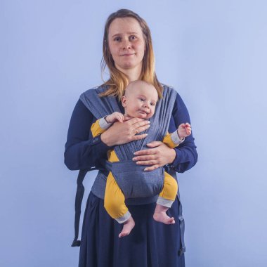 Üç aylık erkek bebek, mavi duvarda annesine askı takıyor.