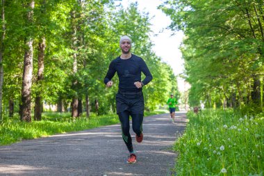 Siyahlı koşan genç adam. Parkta koşuyor. 