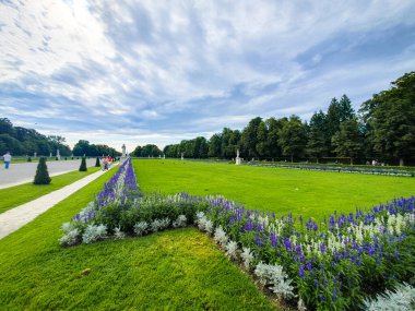 Münih, Almanya 7 Ağustos 2024 - Manikürlü çimenler ve renkli çiçek tarlaları Münih 'teki Nymphenburg Sarayı' nın geniş bahçelerinde yürüyüş yolları