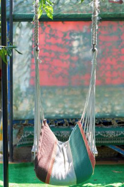 Halatlardan yapılmış bir hamak kırsaldaki bir dinlenme alanında asılı duruyor. Yakın çekim, dikey çekim