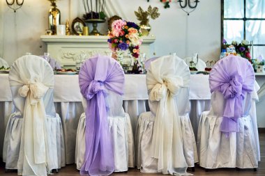 Çok renkli pelerinli sandalyeler festival masasının önünde duruyor.