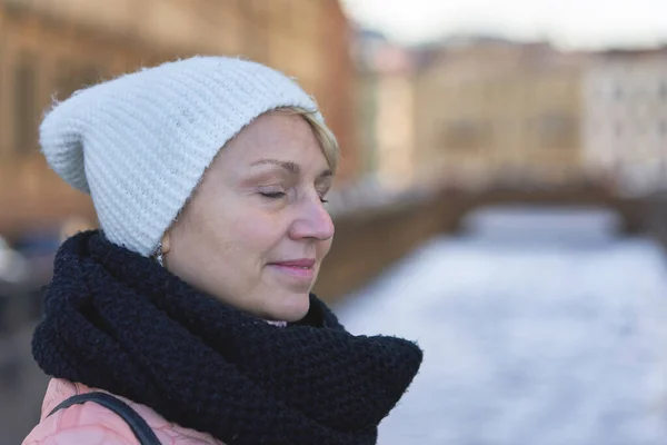 一个戴着黑色围巾 头戴白色帽子 紧闭双眼 站在模糊的城堤后面的女人的画像 — 图库照片