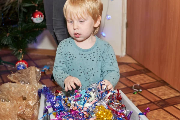 Mały Chłopiec Blond Włosami Siedzi Przed Pudełkiem Błyszczących Świecidełek Choinkę — Zdjęcie stockowe