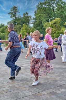 Yaşlı bir çift yaz günü parkta dans ediyor.