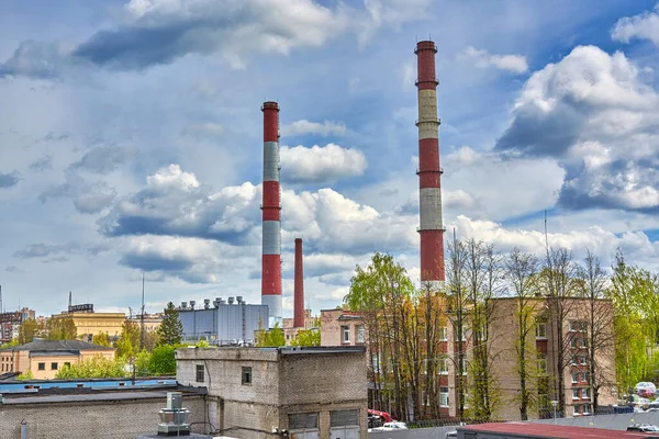 Hohe Fabrikschlote vor wolkenverhangenem Himmel und Wohnhäusern — Stockfoto