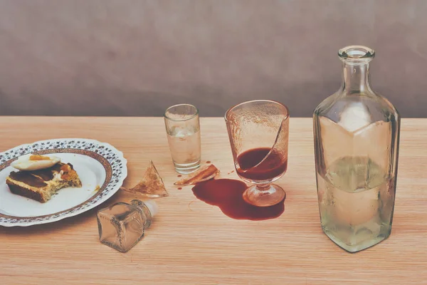 Un bicchiere rotto, succo di pomodoro rosso versato sul tavolo accanto a una bottiglia di vodka — Foto Stock