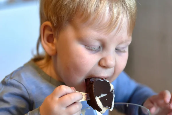 Criança morde sorvete de chocolate em um pau — Fotografia de Stock