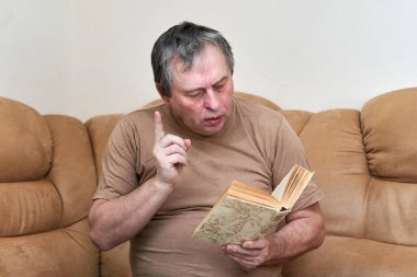 Devani 'de oturan yaşlı bir adam kitap okuyor.