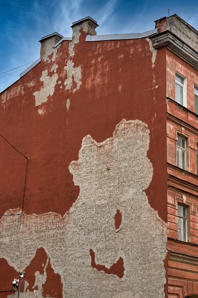 De muur van een oud bakstenen huis met gevallen gips — Stockfoto
