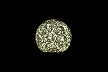 Siyah arka planda beyaz parlayan top, gece lambası karanlıkta parlıyor.