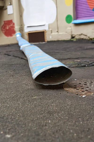 一条城市街道上的沥青路面上有一条长长的下水管 — 图库照片