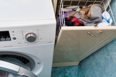 Kirli çamaşırlar için açık bir sepetin yanında çamaşır makinesi.