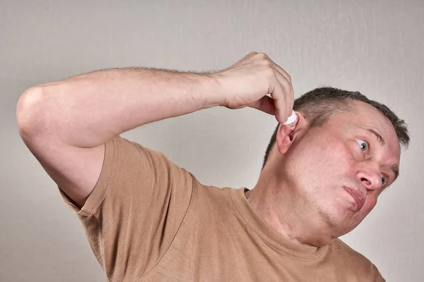 A man instills medicine into his ear with a small pipette from a pharmacy bottle