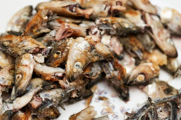 Fish heads and bones left after eating on a plate.