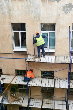 Saint Petersburg, Rusya - 24 Nisan 2021: İşçiler bir binanın ön cephesini onarmak için yapı iskelesi inşa ettiler