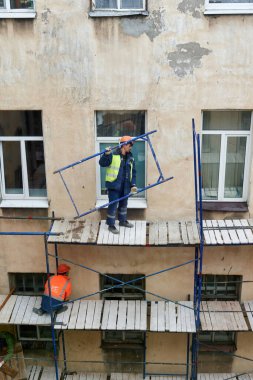 Saint Petersburg, Rusya - 24 Nisan 2021: İşçiler bir binanın ön cephesini onarmak için yapı iskelesi inşa ettiler