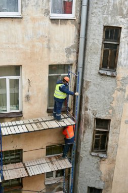 Saint Petersburg, Rusya - 24 Nisan 2021: İşçiler bir binanın ön cephesini onarmak için yapı iskelesi inşa ettiler