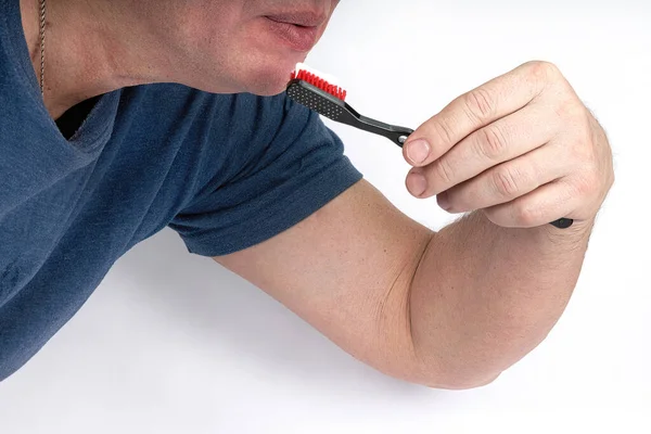 A man brushes his teeth with a black toothbrush with a red shield — Stock Photo, Image