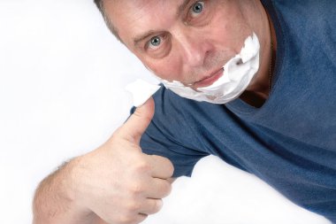 Bir adam tıraş köpüğünü yüzüne bir tıraş fırçasıyla sürer.