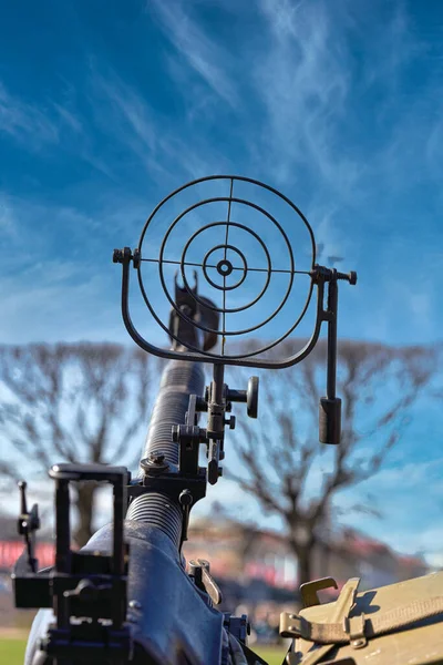 A fragment of an anti aircraft machine gun, a round sight is aimed at the clouds against a blue sky. War and terror concept