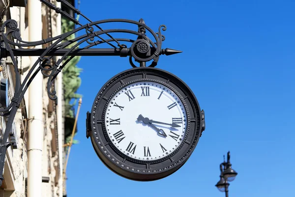 Antike runde Uhr mit römischen Ziffern hängt an der Straße der Stadt — Stockfoto