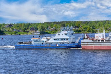 Kıyıya doğru ağır bir mavnayı iten römorkör görüntüsü. Malların nehir taşımacılığı
