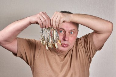 A man holds in his hands a lot of fish gnawed to the bone clipart