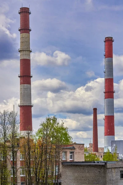 Hohe Fabrikschlote vor wolkenverhangenem Himmel und Wohnhäusern — Stockfoto