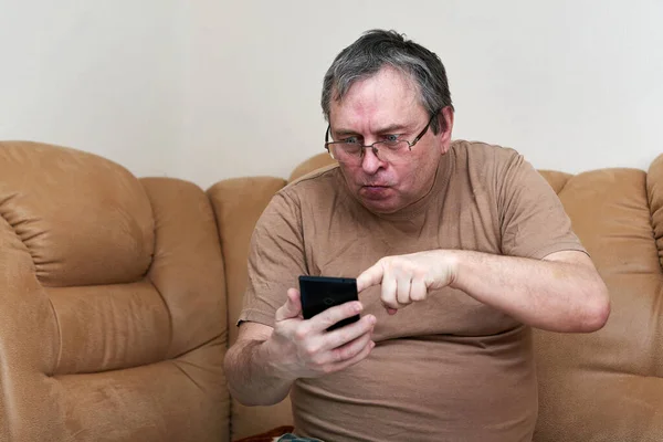 소파에 앉아 있는 노인들은 스마트폰을 능숙하게 하는 기술을 잘 알고 있다 — 스톡 사진