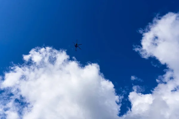 Egy helikopter sziluettje a kék égbolton felhőkkel. — Stock Fotó