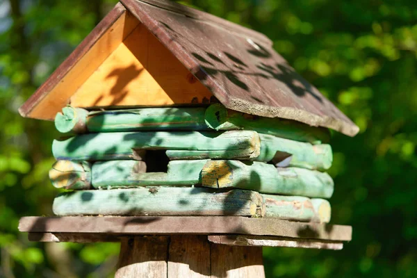 Casa de pájaros de madera en forma de casa en un tocón en el parque —  Fotos de Stock