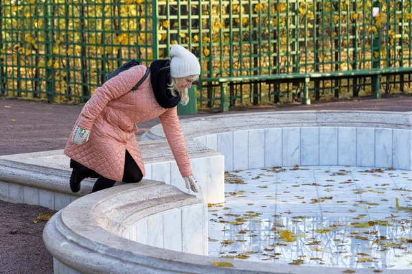Senora im rosafarbenen Mantel in den ausgeschalteten Brunnen gebeugt — Stockfoto