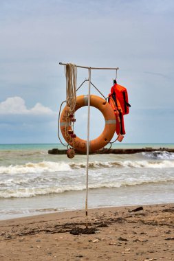 Rescue equipment on the water, lifebuoy and life jacket on the beach. Vertical shot