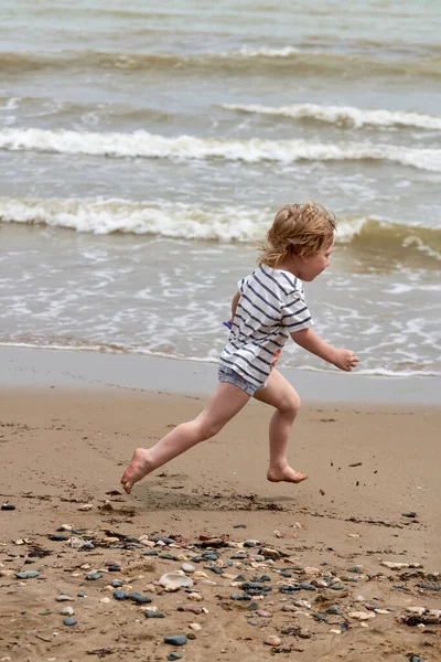 Ένα Μικρό Αγόρι Τρέχει Κατά Μήκος Της Αμμώδους Παραλίας Κατά — Φωτογραφία Αρχείου